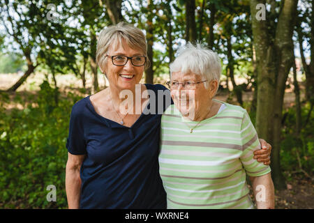 Sehr alte fröhliche ältere Dame mit ihrer Tochter zu Fuß in einem schönen Park, um zusammen glücklich zu sein Stockfoto