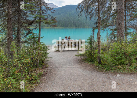 Der Yoho National Park, British Columbia, Kanada - September 08, 2019: Zwei Leute sitzen auf einer Parkbank mit Blick auf Emerald Lake Stockfoto