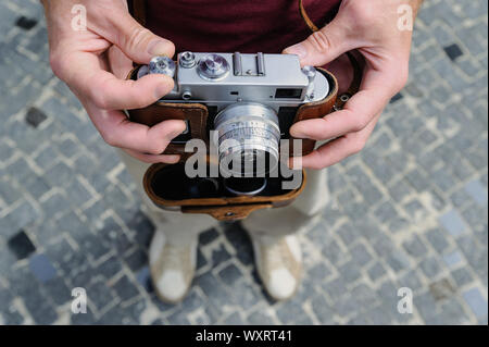 Ein Mann hält ein Vintage Kamera. Mit einer Hand ist es die Einstellung ändern. Ansicht von oben. Stockfoto