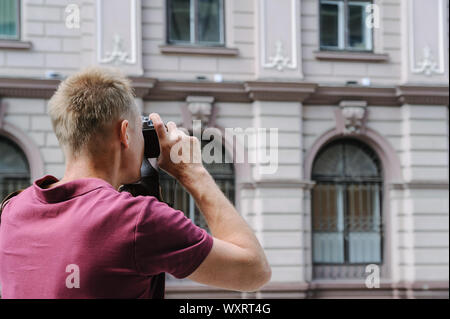 Ein Mann ist Fotografieren ein altes Haus. Er ist mit einem Vintage Kamera. Stockfoto