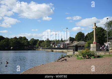 Blick auf die Staumauer mit Straße und steinernes Kreuz an newmillerdam Wakefield Yorkshire England Stockfoto