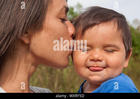 Mutter küssen Baby auf Wange Stockfoto