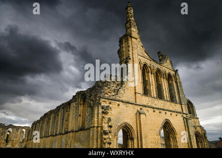 Mittelalterliche große Kirche, die Ruinen von Byland Abbey North Yorkshire England mit dunklen Gewitterwolken mit Sonnenuntergang Stockfoto