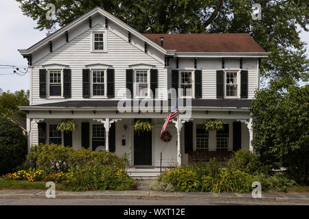 New Paltz, New York - September 6, 2019: Amerikanische Flagge vor der großen traditionellen Haus in ruhiger Nachbarschaft Stockfoto