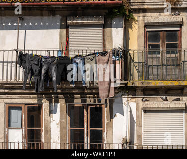 Verschlissene jeans und Hosen trocknen außerhalb der alten Häuser und Apartments in der Innenstadt von Porto Stockfoto