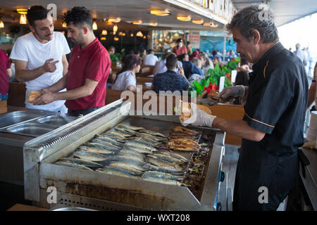 Der Küchenchef bereitet Makrele Fisch, Sandwiches in einem Restaurant unter der Galatabrücke am Goldene Horn in Istanbul Stockfoto