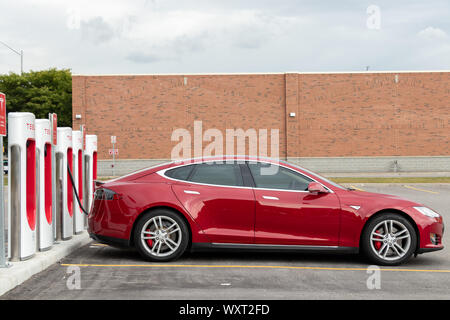 Seite des Tesla Model S, während es angeschlossen ist und am Kompressor aufgeladen wird. Stockfoto