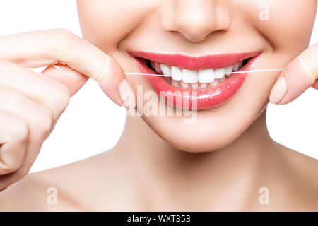 Junge schöne Frau ist bei der Reinigung der Zähne beschäftigt. Schönes Lächeln Gesunde weisse Zähne. Ein Mädchen hält einen Zahnseide. Das Konzept der Mundhygiene. Stockfoto