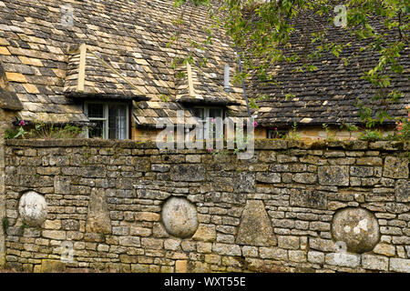 Gelbe Cotswold Kalkstein Wand mit Block formen und Haus mit Schieferdach in Snowshill Gloucestershire England Stockfoto