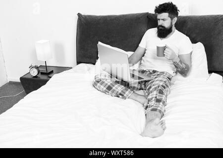 Schnell am Morgen unterhalten. Eine Pause. Zu viel Arbeit. All seine Energie zu arbeiten. Geschäftsmann mit Computer. bärtiger Mann Arbeiten am Laptop. Mann im Schlafzimmer Kaffee trinken. Energie und Müdigkeit. Stockfoto