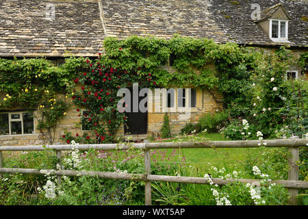 Haus mit gelben Cotswold Mauern aus Kalkstein und Schiefer mit Garten der Blumen und Rosen in Snowshill Gloucestershire England Stockfoto