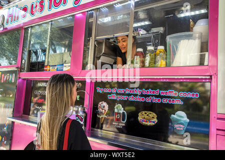 Cypress, CA/USA, Sept. 16, 2019: Schöne junge Frau eine Bestellung am Fenster eines farbenfrohen, Rosa essen Fahrzeug. Stockfoto