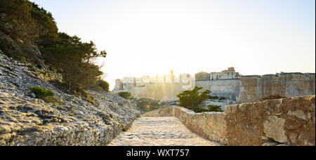 Einen atemberaubenden Sonnenuntergang, ein Weg, der mit dem schönen Dorf von Bonifacio von alten Mauern umgeben leuchtet auf. Südlich von Korsika, Frankreich. Stockfoto