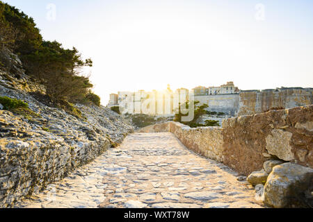 Einen atemberaubenden Sonnenuntergang, ein Weg, der mit dem schönen Dorf von Bonifacio von alten Mauern umgeben leuchtet auf. Südlich von Korsika, Frankreich. Stockfoto