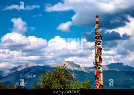 Bunte Totem entlang der Bahnstrecke in Kanada mit den Rocky Mountains im Hintergrund Stockfoto