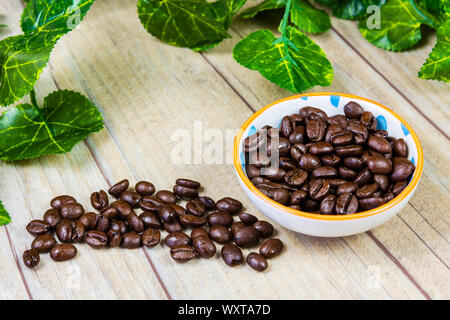 Kaffee Bohnen in einer Schüssel auf einem hölzernen Hintergrund Stockfoto