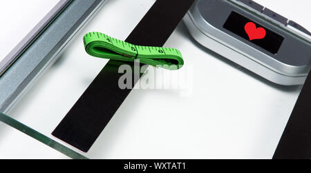 Sliver Personenwaage mit grünen Maßband auf weißem Hintergrund. Gesundheit und Gewichtverlust Konzept Stockfoto