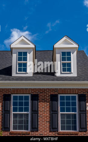 Dachfenster mit doppelte Fenster shutter Windows und Backsteinfassade auf ein Einfamilienhaus mit blauem Himmel Stockfoto