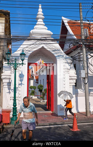 Passanten, die an einem der Tempel Tore des Wat Suthat in der Altstadt von Bangkok, Thailand Stockfoto