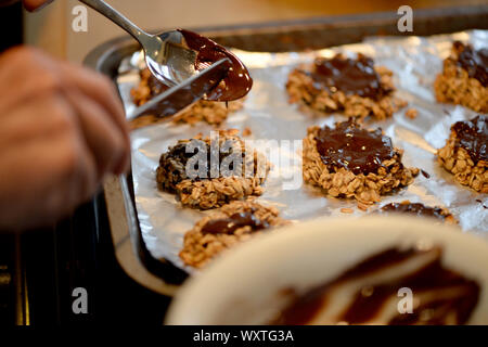 Die Beschichtung der Hafer und Banane cookies mit Schokolade Stockfoto