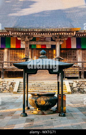 DEC 3, 2018 Yamagata, Japan - Konponchudo Haupthalle inscent Topf in Yamadera Risshaku ji-Tempel mit alten Holz Wand und bunten Buddhismus Flags Stockfoto