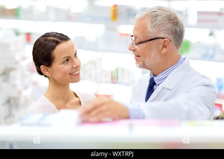 Medizin, Gesundheitswesen und Personen Konzept - ältere Apotheke mit Drogen- und weibliche Kunden an Apotheke Stockfoto