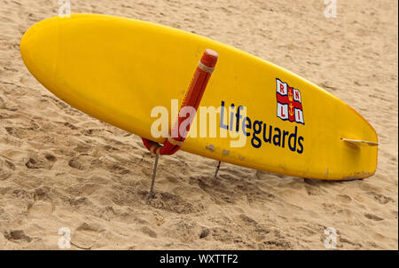 Bereit für Action, ein Rnli sufboard auf Porthmeor Beach St Ives in Cornwall an der Atlantikküste mit Badegästen und Surfern beliebt Stockfoto