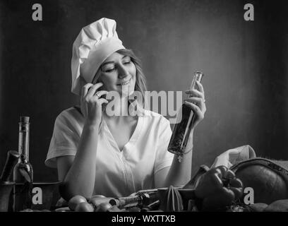 Junge schöne Mädchen in ein Chef Uniform mit kleinen Flaschen Olivenöl. Duftende Olivenöl mit verschiedenen Gewürzen und Kräutern. Stockfoto