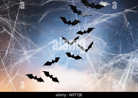 Halloween, Dekoration und beängstigend Konzept - schwarz Fledermäuse über Sternenhimmel und spiderweb Hintergrund fliegen Stockfoto