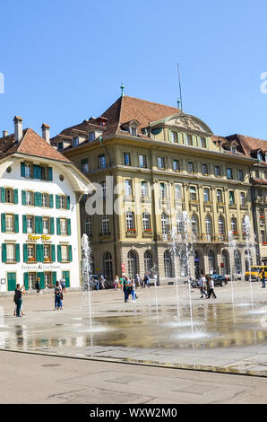 Bern, Schweiz - 14 August 2019: Bundesplatz, der Platz in der historischen Altstadt von der Schweizer Hauptstadt mit Menschen. Traditionelle Gebäude, Cafes, Restaurants. Wasserfontänen. Sommertag. Stockfoto