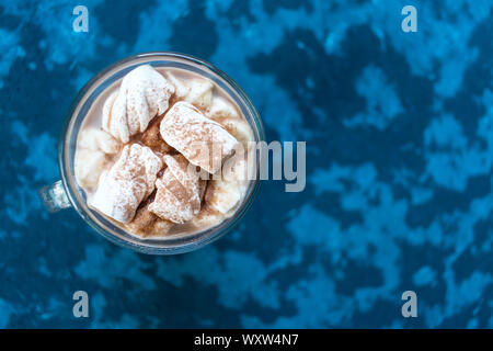 Ein Glas heißer Kakao mit Marshmallows auf einem blauen Hintergrund. Ansicht von oben. Kopieren Sie Platz. Stockfoto