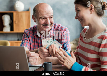 Olderly spanische Mann gibt seine Tochter Geld für eine Hypothek oder Darlehen. Hilfe für Kinder und Rentner. Stockfoto