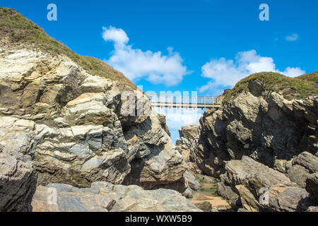 Eine Fußgängerbrücke über die schroffe Kluft zwischen dem Festland und Porth Insel mit einer Spring Tide in Newquay in Cornwall ausgesetzt. Stockfoto