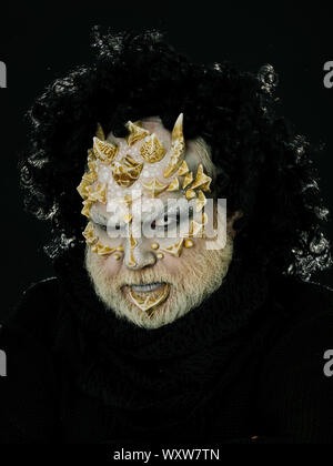 Monster Mann mit weissen Augen in Schwarz Perücke finsteres Gesicht auf dunklem Hintergrund. Horror und Fantasy Konzept Stockfoto