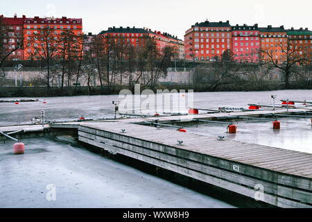 Bootsliegeplätze im Eis von Karlberg See (Karlbergssjon) mit bunten Fassaden der Häuser, Atlas Stadtteil Norrmalm, Stockholm, Schweden eingefroren Stockfoto