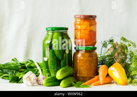 Fermentierte oder canning verschiedene Gemüse zucchini Karotten Gurken in Gläsern auf einem Tisch, einem hellen Hintergrund. Verarbeitung der Herbst Ernte. Natürliche Tropfen Stockfoto