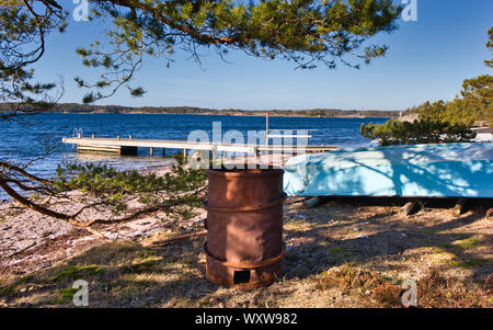 Rost barrel, Umgedrehten blauen Boot und rustikaler Holzsteg an der Ostsee, Sandhamn, Stockholmer Schären, Schweden Stockfoto