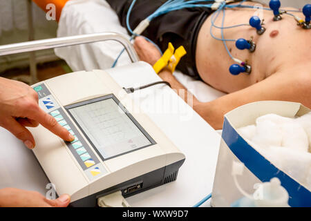 Kardiologe mit EKG-Geräte, Elektrokardiogramm Test des Patienten, der mit Vakuum Sensoren an der Maschine befestigt ist. Stockfoto