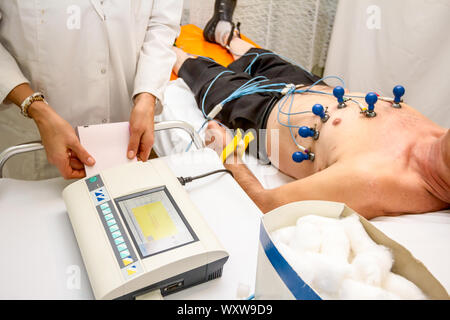 Kardiologe mit EKG-Geräte, Elektrokardiogramm Test des Patienten, der mit Vakuum Sensoren an der Maschine befestigt ist. Stockfoto