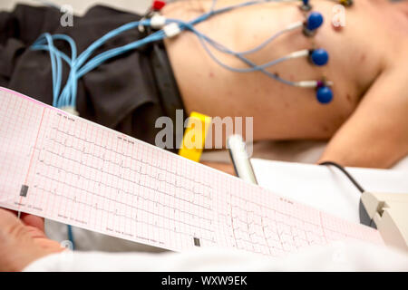 Der kardiologe Holding und Überprüfung des Elektrokardiographen EKG oder EKG-Diagramm auf Raster Papier gedruckt. Stockfoto