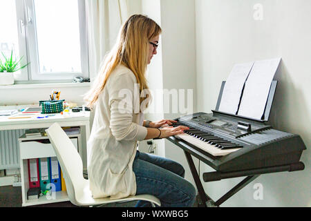 Junge schöne Frau am Klavier zu Hause spielen Stockfoto