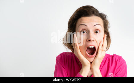 Bild einer aufgeregt schreienden jungen Frau, die in einem rosa Bluse isoliert über einen hellen Hintergrund. Stockfoto