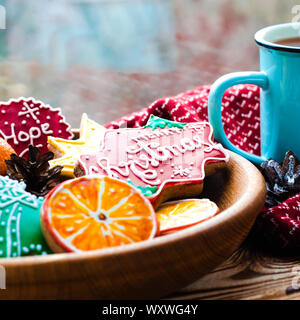 Eine heiße Tasse Tee steht auf einem hölzernen Tisch neben einem hölzernen Platte auf die Lebkuchen Cookies von orange Schnitte vor dem Hintergrund einer Stockfoto