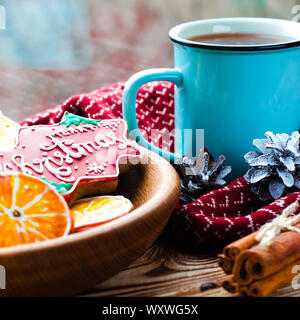 Eine heiße Tasse Tee steht auf einem hölzernen Tisch neben einem hölzernen Platte auf die Lebkuchen Cookies von orange Schnitte vor dem Hintergrund einer Stockfoto