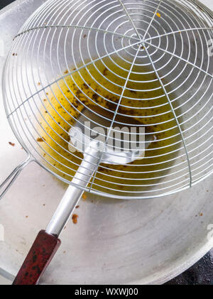 Großes Sieb auf dem Metall Pfanne mit Speiseöl nach Fried die Kartoffelchips. Stockfoto
