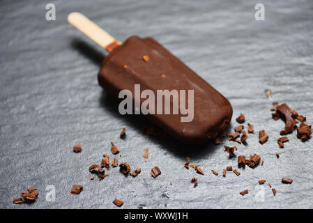 Ice Cream Stick mit Mutter Mandeln auf dunklem Hintergrund, Flach/Eis bedeckt chocolate Sticks gefroren Popsicle und Lolly süßes Dessert Stockfoto