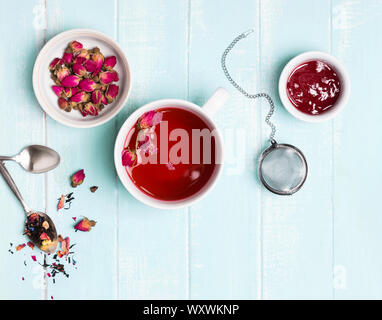 Blumen Tee mit trockenen Rosen auf Pastell mint oder blau Holz- Tabelle, Ansicht von oben. Stockfoto
