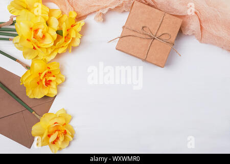 Frühjahr Zusammensetzung mit gelben Blumen, geschenkset und andere Objekte auf dem weißen Holz- Tabelle, Ansicht von oben Stockfoto
