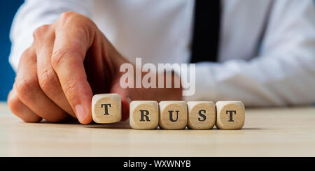 Hand eines Geschäftsmannes Montage das Wort Vertrauen geschrieben auf Holz Würfel. Stockfoto
