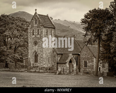 Die kleinen alten Kirche im Dorf Ilam, Staffordshire mit den Hügeln des Peak District National Park im Hintergrund. Sepia getonten Bild Stockfoto